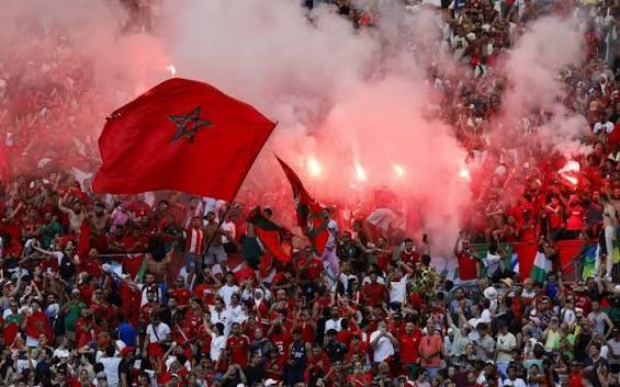Morocco supporters raising red flags inside a stadium — representing the national support base the Grand Stade Hassan II is designed to unite.