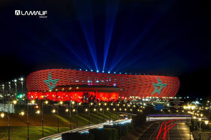 Architectural rendering of the Grand Stade Hassan II illuminated exterior at night — showing the proposed lighting and facade design.