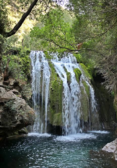 Hikers approaching Akchour's river gorge and falls in the Rif Mountains