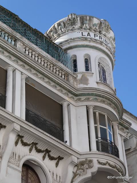 Ornamented corner façade with wrought-iron balcony and green glazed roof tiles in Casablanca