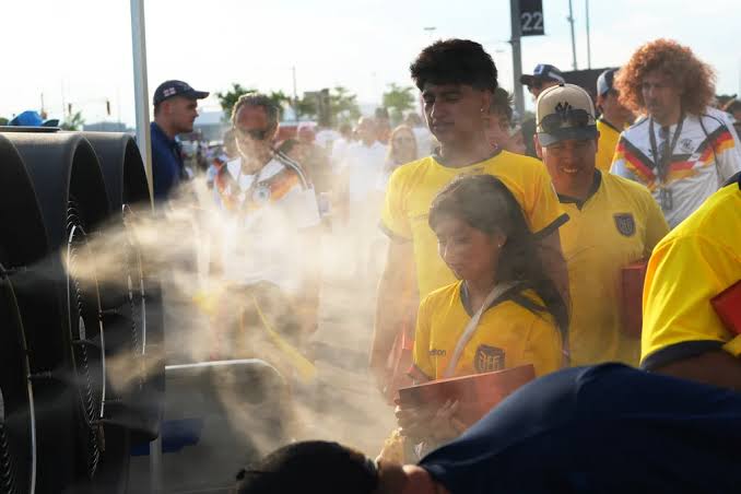 Supporters seek water and shade during a summer football event.