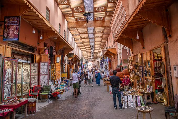 Narrow souk lane in Marrakech medina with hanging lanterns and crafts
