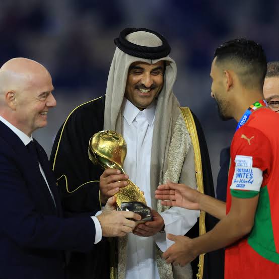 A Morocco captain receives the FIFA Arab Cup trophy from FIFA president Gianni Infantino and the Emir of Qatar, December 2025