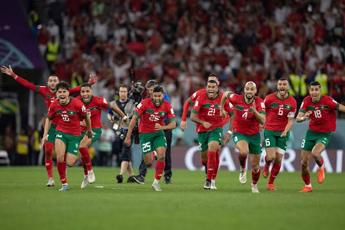 The entire Atlas Lions squad sprint together in celebration after Morocco's penalty shootout victory at the 2022 World Cup in Qatar