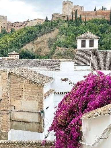 Whitewashed houses and tiled roofs in Granada below the walls and towers of the Alhambra