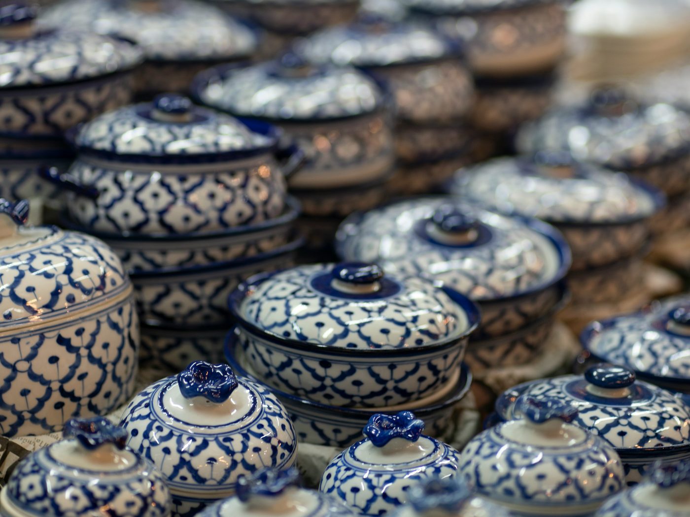 Rows of lidded ceramic pots painted in cobalt-blue patterns on a white glaze