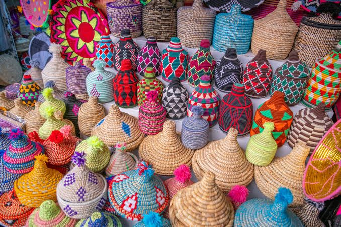 Stacks of woven baskets with conical lids in natural and dyed colours in a market