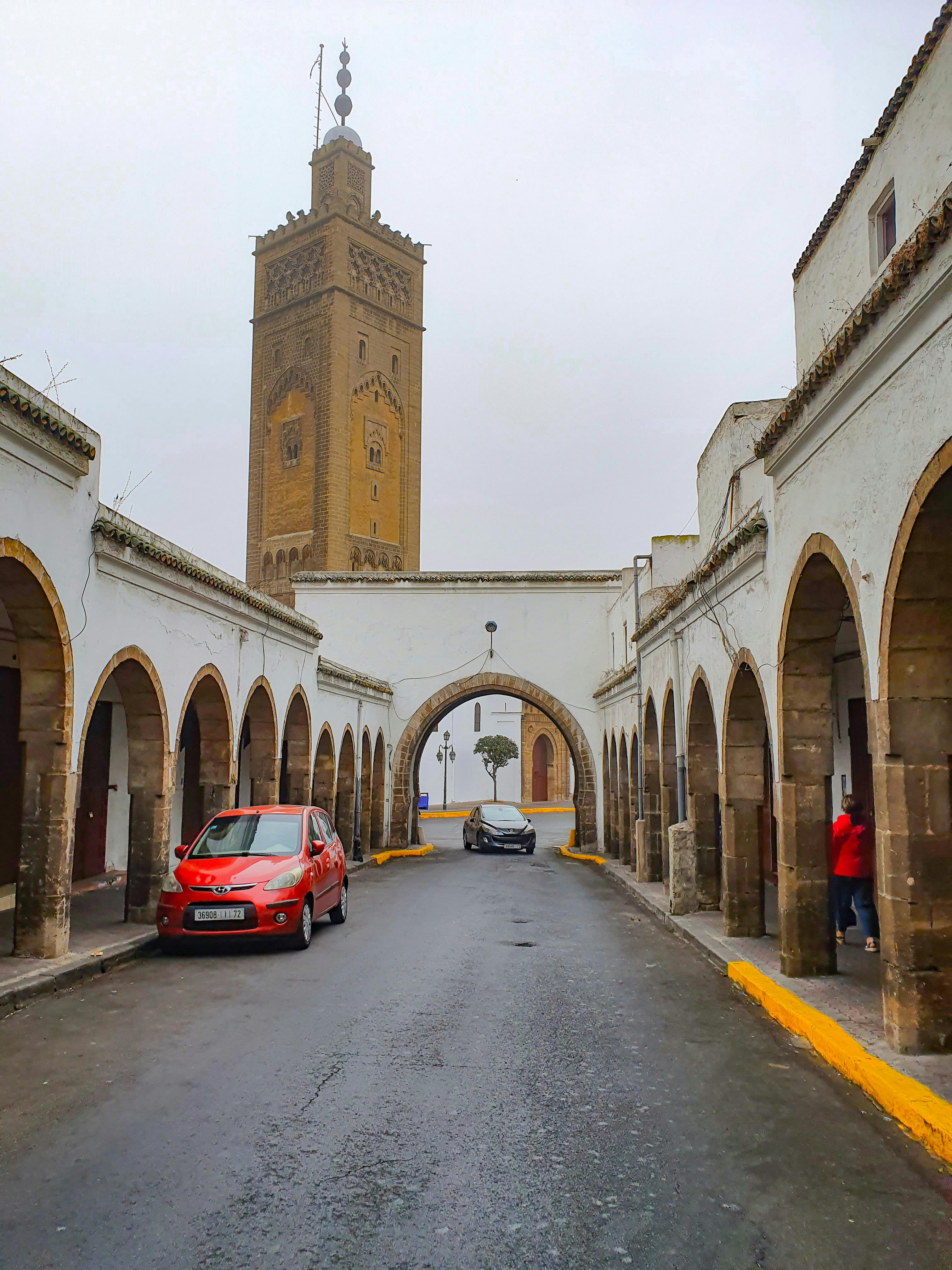 A car before one of the great monumental gates that define the approach to Morocco's imperial cities — these gates were not merely entrances but declarations of dynastic power, marking the threshold between the ordinary world and the seat of the kingdom