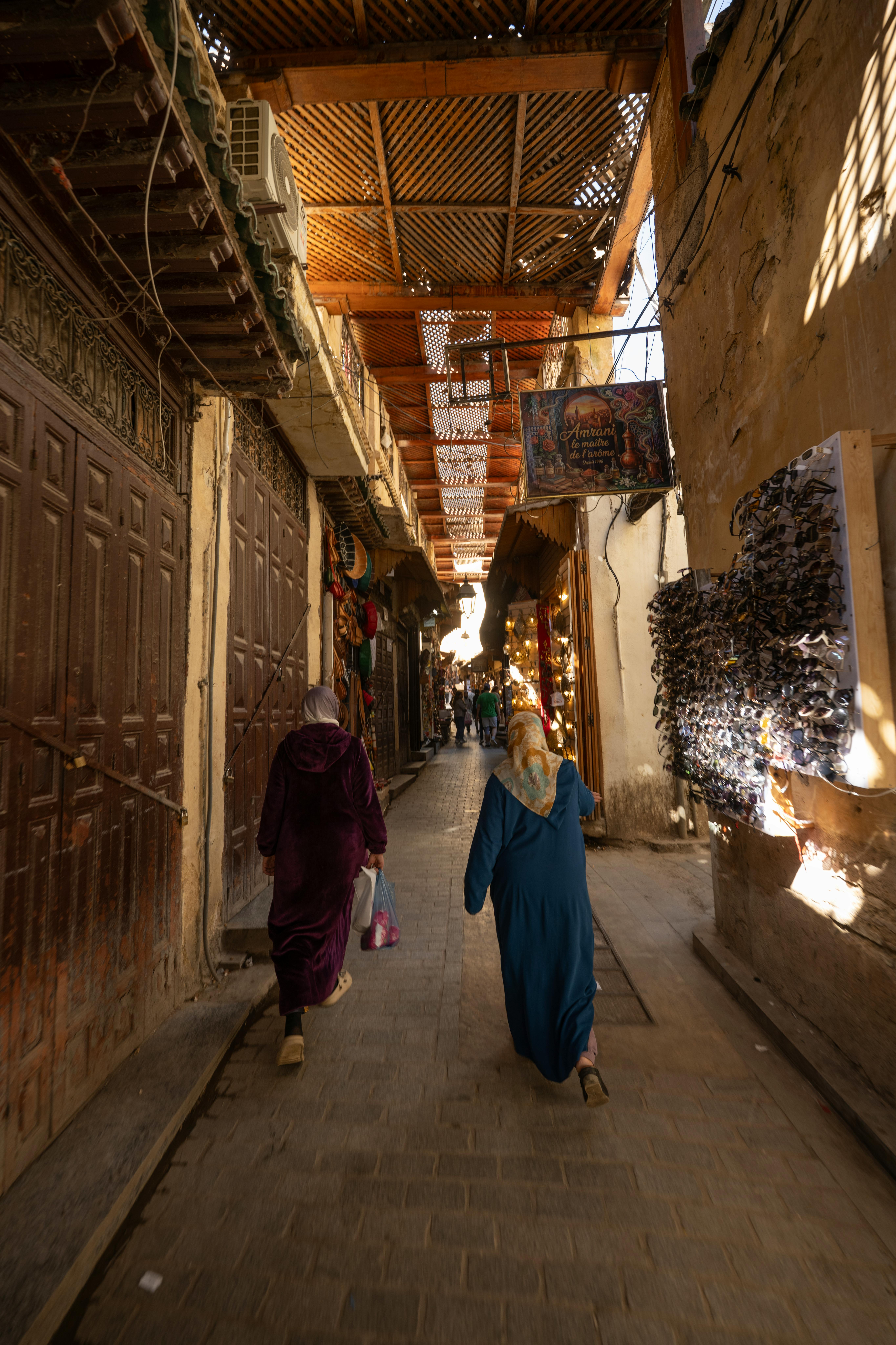 Women in djellabas walking through the covered souks of Fes el-Bali